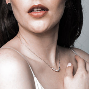 A woman wearing a delicate silver necklace.