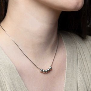 Woman elegantly wearing a Small 5 Ball Necklace in silver, featuring movable balls on a snake chain, epitomizing timeless, everyday elegance.