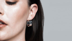 Close-up of a woman showcasing Sophie Anna's chunky sterling silver hoop earrings, handcrafted from recycled sterling silver, highlighting the brand's dedication to sustainable craftsmanship.