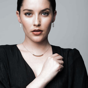 A woman wearing a dainty gold necklace with co-ordinating pearl drop earrings.