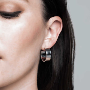 Close-up of a woman showcasing Sophie Anna's chunky sterling silver hoop earrings, handcrafted from recycled sterling silver, highlighting the brand's dedication to sustainable craftsmanship.
