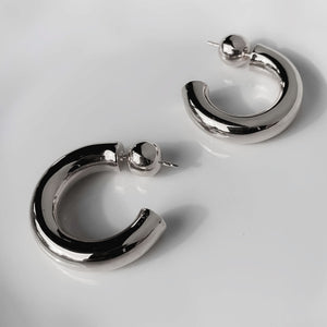 Close-up view of elegant sterling silver tube hoop earrings displayed against a minimalist background, perfect for sophisticated everyday wear - Sophie Anna Collection.