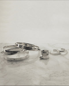Timeless silver heirloom jewelry collection on marble - featuring recycled sterling silver bangles, rings and earrings with pearl accents. Ethical, sustainable jewelry pieces designed to be cherished for generations.