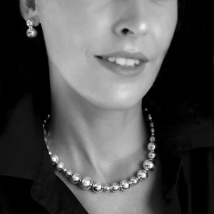 Close-up of a person wearing a silver statement necklace and earrings.