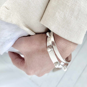 two sterling silver bangles one with set with pearls on a wrist