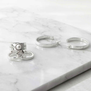 Set of silver pearl rings on a marble surface