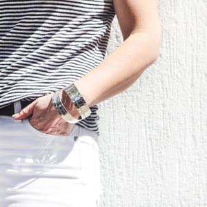 A stack of solid sterling silver bangles on a woman's arm.