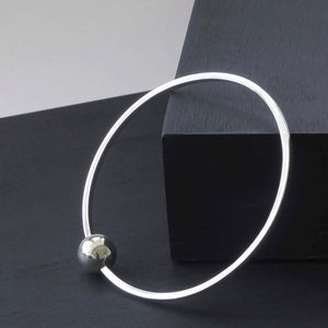 Elegant Single Ball Bangle crafted from recycled sterling silver, featuring a unique sliding ball on a flat-edged band, exemplifying lightweight and versatile style for effortless wardrobe integration