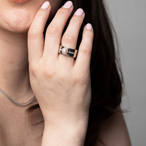 a wide sterling silver band ring with a large pearl and 5 diamonds on either side of pearl