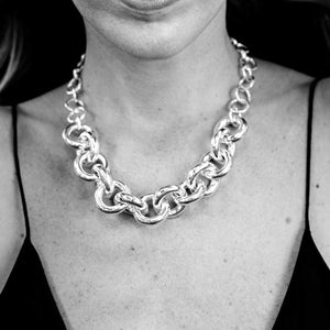 Close-up of a woman wearing a handcrafted recycled sterling silver chain link statement necklace. The necklace features bold custom links and a rolo chain, adding a touch of modern elegance.