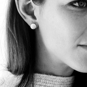 Woman showcasing 10mm flat disc stud earrings in gold vermeil, with a high-polished finish and matte brushed sides, epitomizing chic everyday wear.