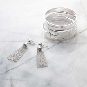 A contemporary jewellery set for woman, a stack of minimal style bangles with co-ordinating tassel earrings.