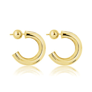 Close-up view of SOPHIE ANNA gold tube hoop earrings elegantly displayed against a white background.