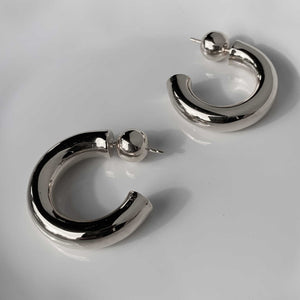Close-up of elegant sterling silver hoop earrings on a white background.